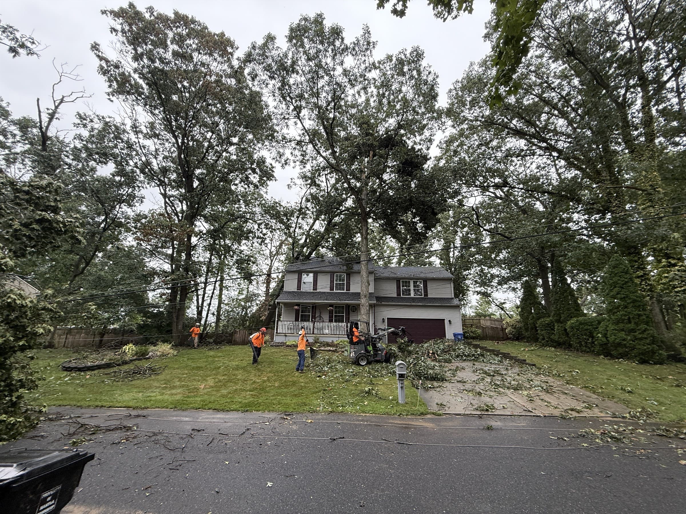 Meinhart's Tree Service crew clearing storm debris outside a Mantua Township home